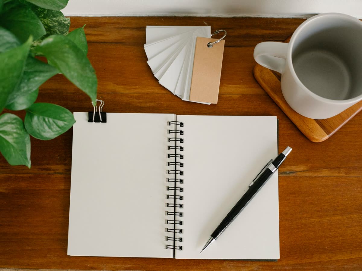 Taccuino, penna e tazza su una scrivania